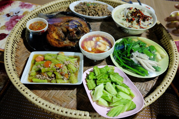 Homemade cooking for Boiled vegetables, chili paste, Deep fried Snapper with fish sauce and Fried Pumpkin with Eggs on Woven tray is tradition Thai local food.