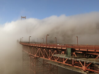 Golden Gate Bridge is getting surrounded by heavy fog as the cars are passing through. - Powered by Adobe