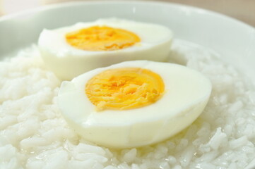 boiled egg half cut topping rice porridge in bowl on table