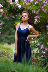 beautiful girl in a long evening dress in a beautiful garden with blooming roses