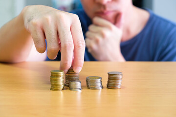 Selective focus of Asian men hand planning and put coin in stack. Personal financial or saving management concept, Wealth and earning more income,