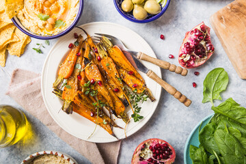 Variety of healthy vegan snacks, gourmet dips. Hummus,  roasted carrots, rice with tempeh in ceramic bowls viewed from above, plant based food
