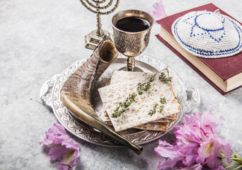 Metal plate with matzah or matza, Kiddush Cup, Shofar horn  on a light  background presented as a...