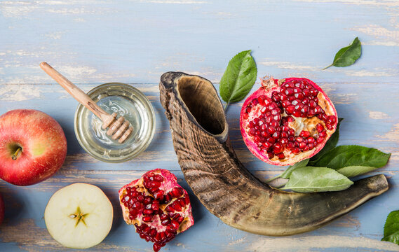 Rosh hashanah  (Hashana) - jewish New Year holiday concept. Traditional symbols: Honey jar and fresh apples with pomegranate and shofar - horn on a blue background. Copy space for text. 