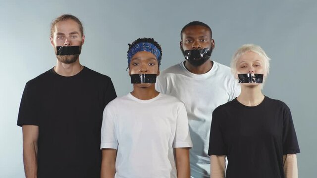 Group of people with tape on mouth look at camera grey background silence gender freedom equality discrimination movement crisis citizen censorship international slow motion