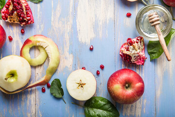 Rosh hashanah  (Hashana) - jewish New Year holiday concept. Traditional symbols: Honey jar and fresh apples with pomegranate and shofar - horn on a blue background.  View from above