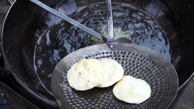 Many Kochuris are being fried in a frying pan. Kochuri, kachori of kachauri is a spicy delicious snack, fried dumpling and a very popular street food in India.