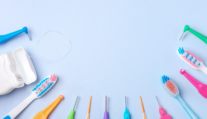 Different interdental toothbrushes, dental floss and toothbrushes on blue background. Dental and...
