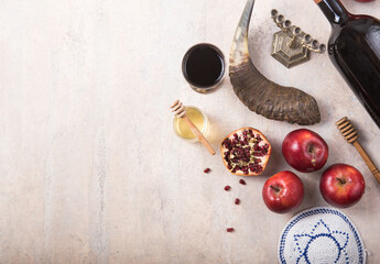 Rosh hashanah - jewish New Year holiday concept. Traditional symbols: Honey jar and fresh apples with pomegranate and shofar-horn, Prayer book. Copy space for text. View from above