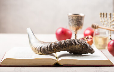 Rosh hashanah - jewish New Year holiday concept. Traditional symbols: Honey jar and fresh apples with pomegranate and shofar-horn, Prayer book. Copy space for text. View from above