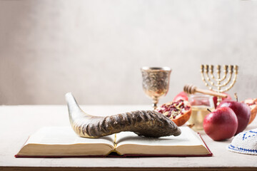 Rosh hashanah - jewish New Year holiday concept. Traditional symbols: Honey jar and fresh apples with pomegranate and shofar-horn, Prayer book. Copy space for text. View from above