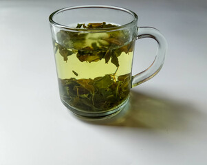 Moringa oleifera as herbal tea, inside transparent glass, isolated in white background