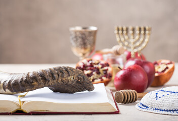 Rosh hashanah - jewish New Year holiday concept. Traditional symbols: Honey jar and fresh apples with pomegranate and shofar-horn, Prayer book. Copy space for text. View from above
