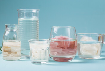 Spring fresh white, pink roses distorted through liquid water of  glass on blue.