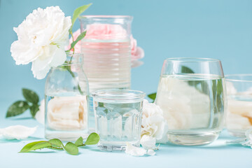 Spring fresh white, pink roses distorted through liquid water of  glass on blue.