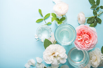 Fototapeta na wymiar Spring fresh white, pink roses distorted through liquid water of glass on blue.