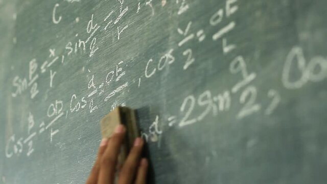 Hand of student cleaning formula of mathematic on blackboard