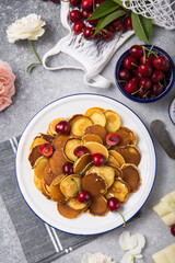  Trendy food, mini cereal pancakes with cherry in bowl on the table, grey cement background.