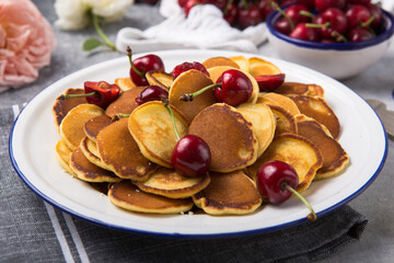  Trendy food, mini cereal pancakes with cherry in bowl on the table, grey cement background.