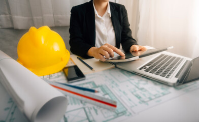 Two colleagues discussing data working and tablet, laptop with architectural project at construction site at desk in office