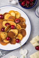  Trendy food, mini cereal pancakes with cherry in bowl on the table, grey cement background.