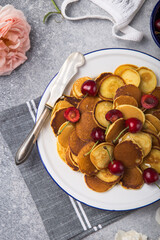  Trendy food, mini cereal pancakes with cherry in bowl on the table, grey cement background.
