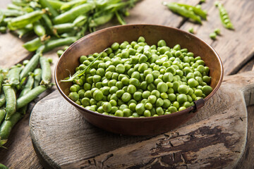 Young fresh green peas on wooden  table viewed from above