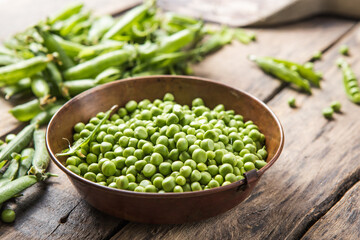 Young fresh green peas on wooden  table viewed from above