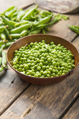 Young fresh green peas on wooden  table viewed from above