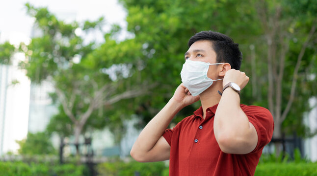 close up asian man wearing protective face mask at park outdoor to protect coronavirus and pollution from environment for new normal behavior lifestyle concept