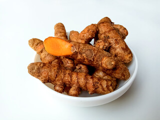 Turmeric or Curcuma longa rhizomes in a bowl, isolated in white background