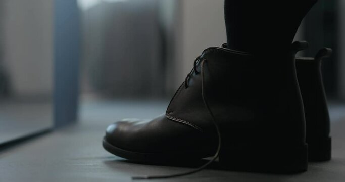 Slow motion young man put on his brown leather chukka boots indoor