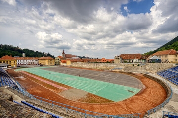 Fototapeta na wymiar BRASOV, ROMANIA - Circa 2020: empty sport stadium and running track with moody cloudy sky. Concept of outdoor activities. No outdoor activity due to lock down.