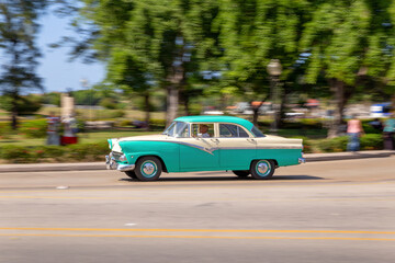 HAVANA, CUBA - CIRCA 2017: Panning on an American blue classic car in the streets of Havana, transporting tourists. Concept of tourism having fun.