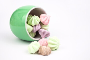 Meringue on a white background. Multi-colored meringues in a green cup on a white background....