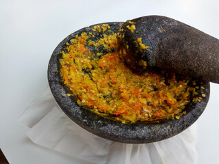 Sambal or traditional chili sauce from Indonesia, freshly made using stone mortar and pestle, isolated in white background