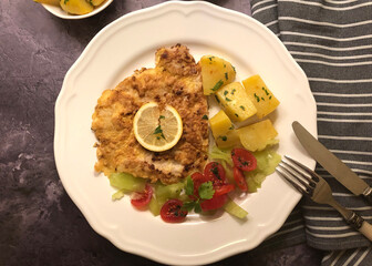 Schnitzel Parisian Style with parsley potatoes and lemon. 
