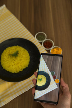 Cooking rice with Curcuma Longa, turmeric or Zerdecal for healthy life and taking photo with smart mobile phone.