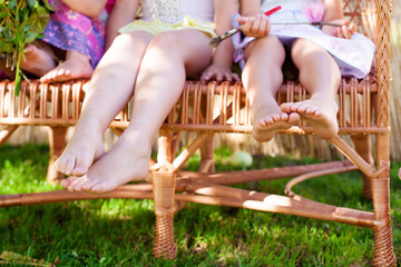 Children's bare feet. Children sit in a wicker chair