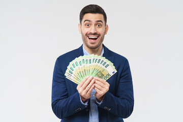 Businessman holding fan of euro notes in hands, feeling excited, amazed and happy about becoming rich, isolated on gray background - obrazy, fototapety, plakaty