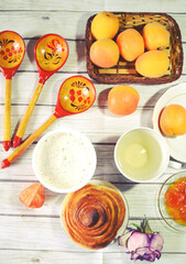 Food still life with Icelandic thick cultured milk called skyr, twist of bread, apricot jam, fresh apricots, green tea cup, wooden spoons as concept for healthy breakfast. Organic diet meal. 