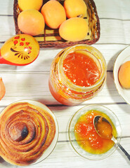 Healthy breakfast on the table with green tea cup, fresh apricots, apricot jam in the glass bottle,  twist of bread. Healthy life style. Food still life. Weight control and diet meal. 