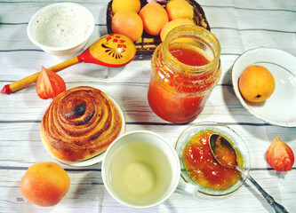 Healthy breakfast on the table with green tea cup, fresh apricots, apricot jam in the glass bottle,  twist of bread. Healthy life style. Food still life. Weight control and diet meal. 
