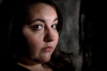 Vintage photo style image of Plus size BBW brunette woman posing in a low key