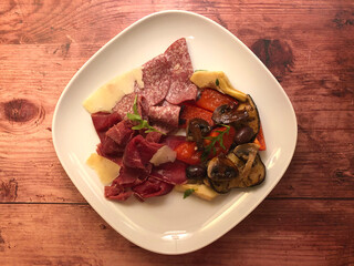 Appetizer plate. Italian ham, salami, grilled vegetables mushroom, zucchini, and arugula salad with parmesan cheese.