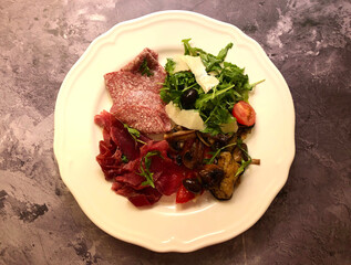 Appetizer plate. Italian ham, salami, grilled vegetables mushroom, zucchini, and arugula salad with parmesan cheese.