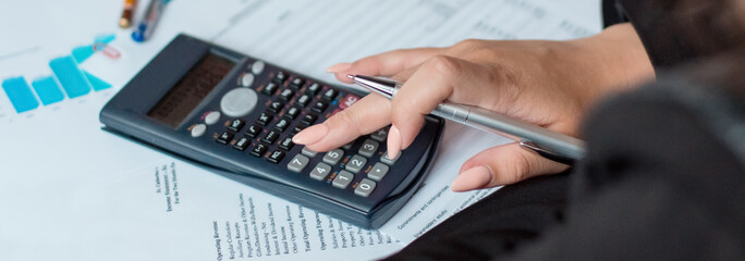 Businesswoman using a calculator to calculate the numbers