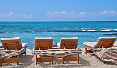 These lounge chairs are just waiting for someone to slip into to sun bathe in, on this beautiful tropical beach.  Turquoise colored ocean water and white sands of Hawaii.