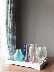 Mid-century modern glass vases in blue and green interior, before the window