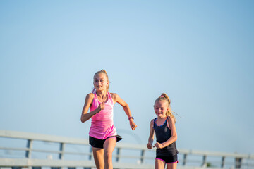 Girls compete on the asphalt road against the evening sky